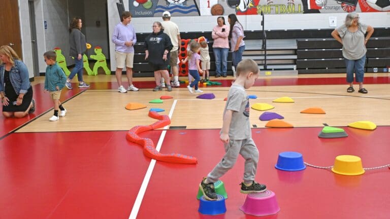 Child navigating colorful stepping obstacles in school gymnasium during early intervention activity program in Ohio