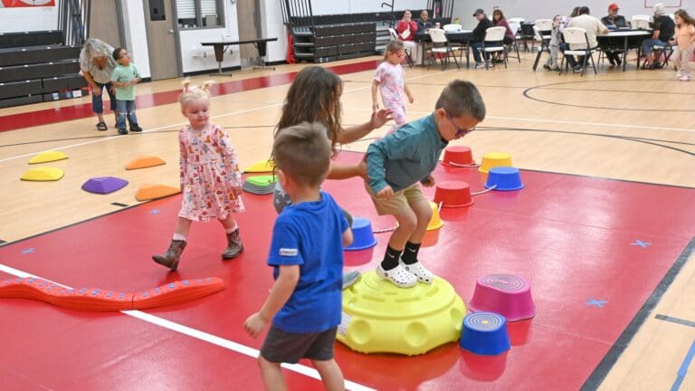Young children participating in a developmental activity program, navigating obstacle course equipment in a gymnasium in Sandusky County, Ohio