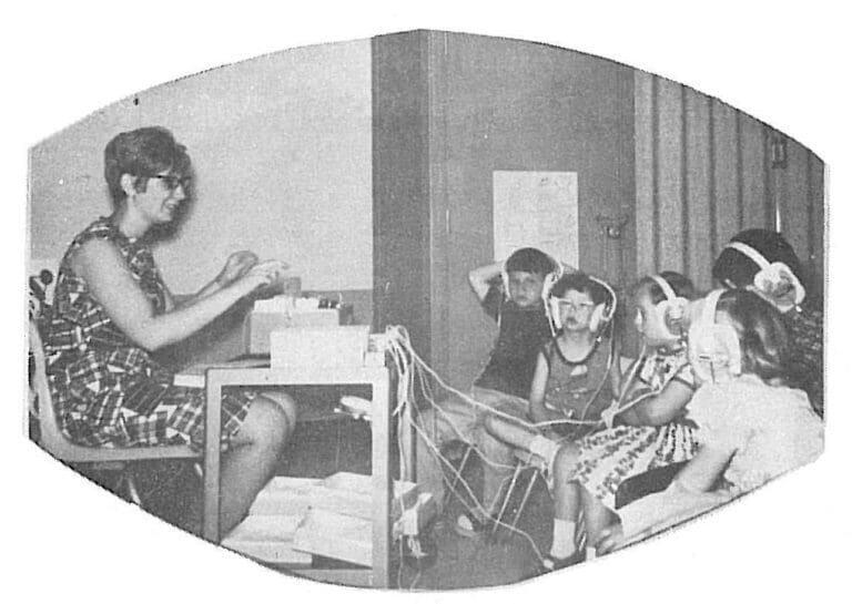 Woman conducting early intervention session with children wearing headphones in Sandusky County, Ohio developmental services classroom