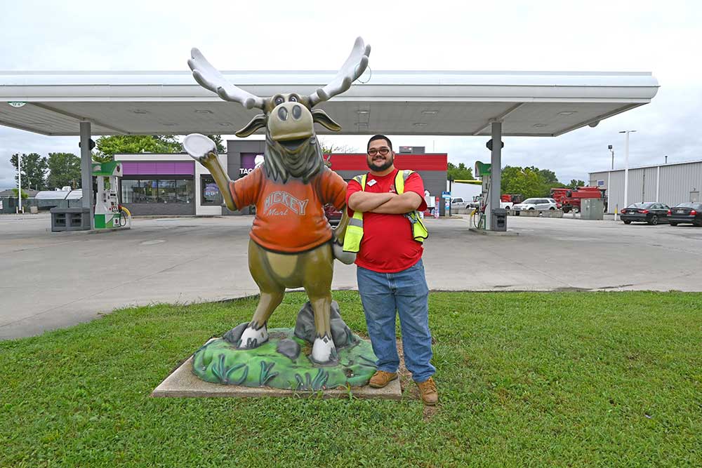 Man in red shirt posing with moose mascot statue at gas station in Sandusky County Ohio