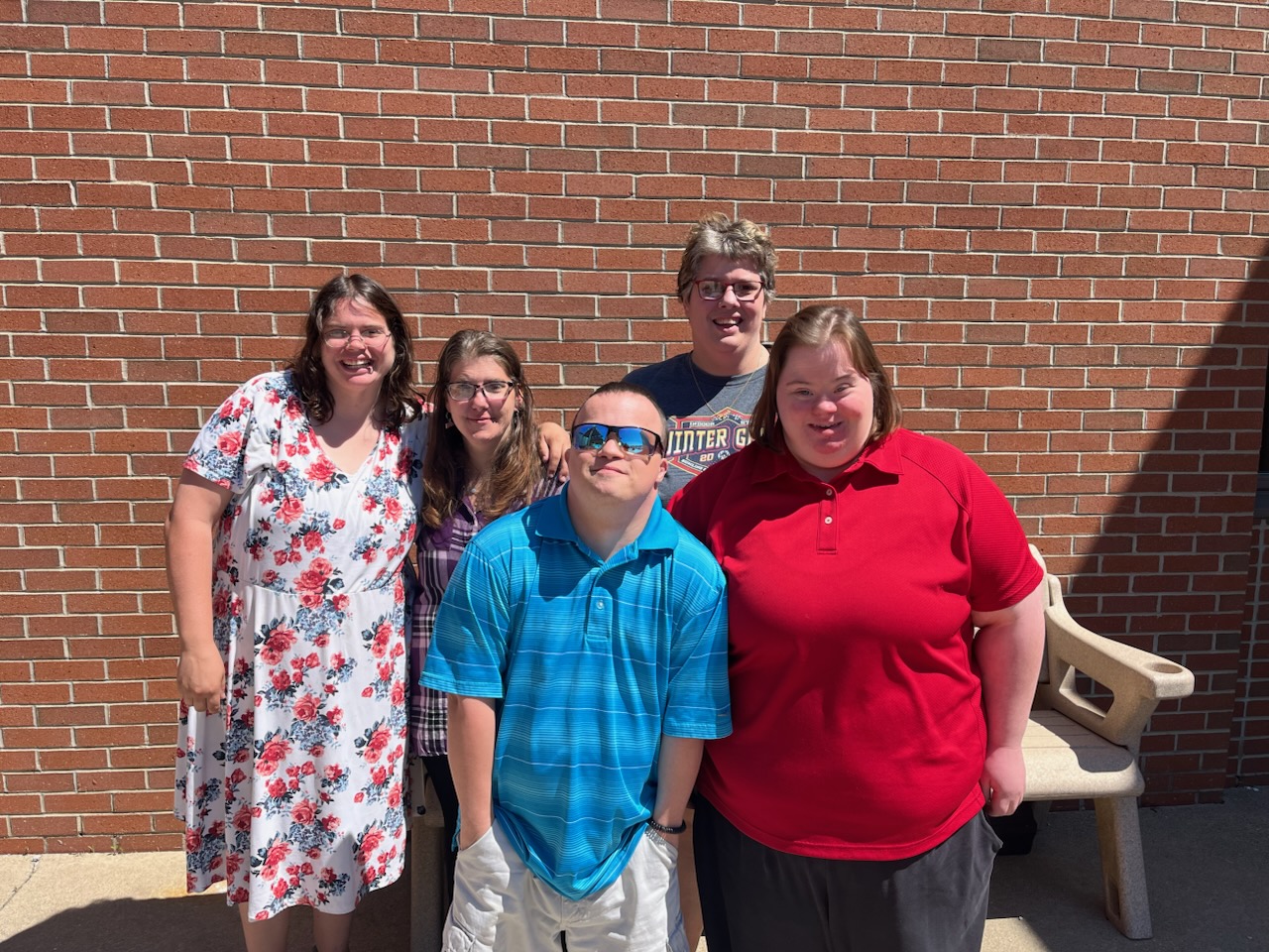 Five smiling teens and young adults posing together in front of a brick wall in Sandusky County, Ohio
